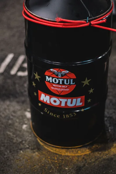 Motorolajos fém hordó garázs padlóján, márkajelzéssel