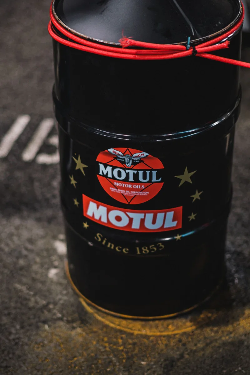 Motorolajos fém hordó garázs padlóján, márkajelzéssel